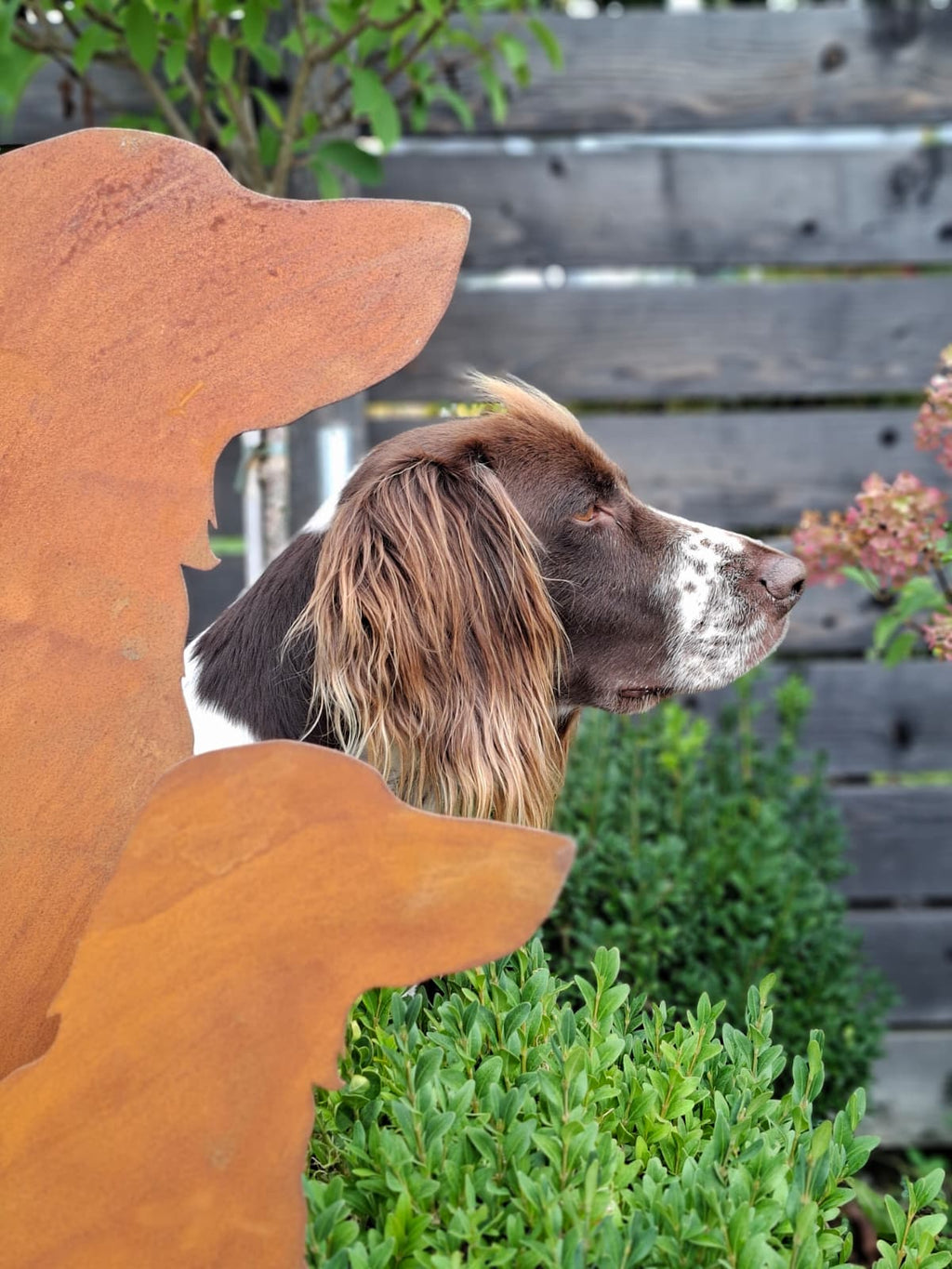 Gartenfiguren in Rostoptik im Detail mit einem Jagdhund zwischen der großen und kleinen Silhouette