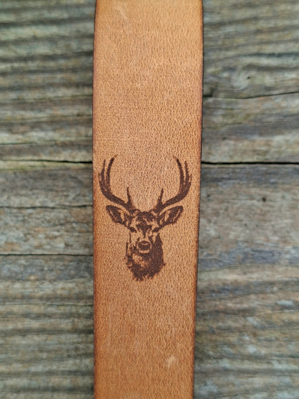 Brauner Leder-Schlüsselanhänger mit graviertem Hirschkopf auf einem Holztisch