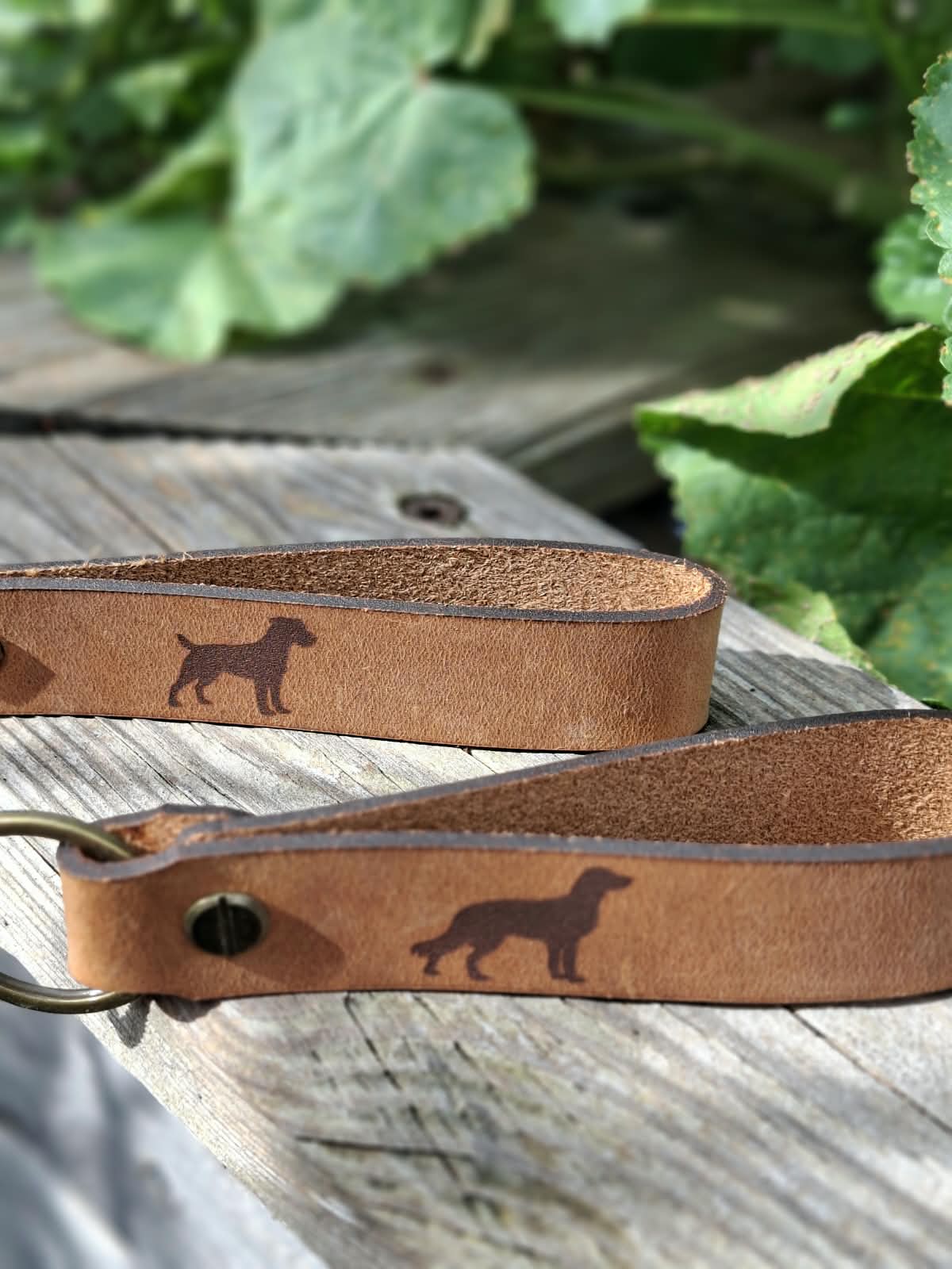 Leder-Schlüsselanhänger mit zwei unterschiedlichen Hundesilhouetten auf verwittertem Holz